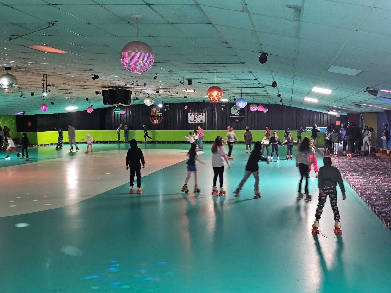 Skaters on the rink floor under disco lights and party decorations at Hartsville Skating Arena